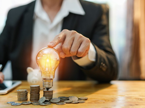 Touching lightbulb surrounded by coins